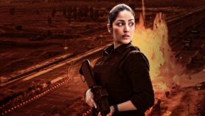 Actress in black combat attire standing with a rifle against a fiery background in the movie Article 370