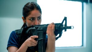 Close-up of an actress aiming a rifle in a tactical vest from the movie Article 370.