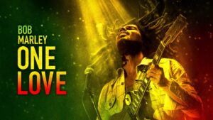 : "Bob Marley: One Love movie poster with Bob Marley playing the guitar under a spotlight."