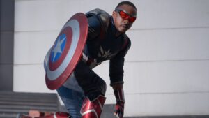 Sam Wilson, suited as Captain America, crouches with his shield ready for action in Captain America: Brave New World, embodying the legacy of the iconic hero.