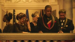 "Formal gathering of leaders watching from a balcony in Rebel Ridge"