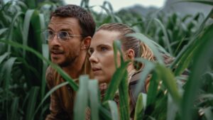 Two main characters hiding in tall grass in Jurassic World Rebirth